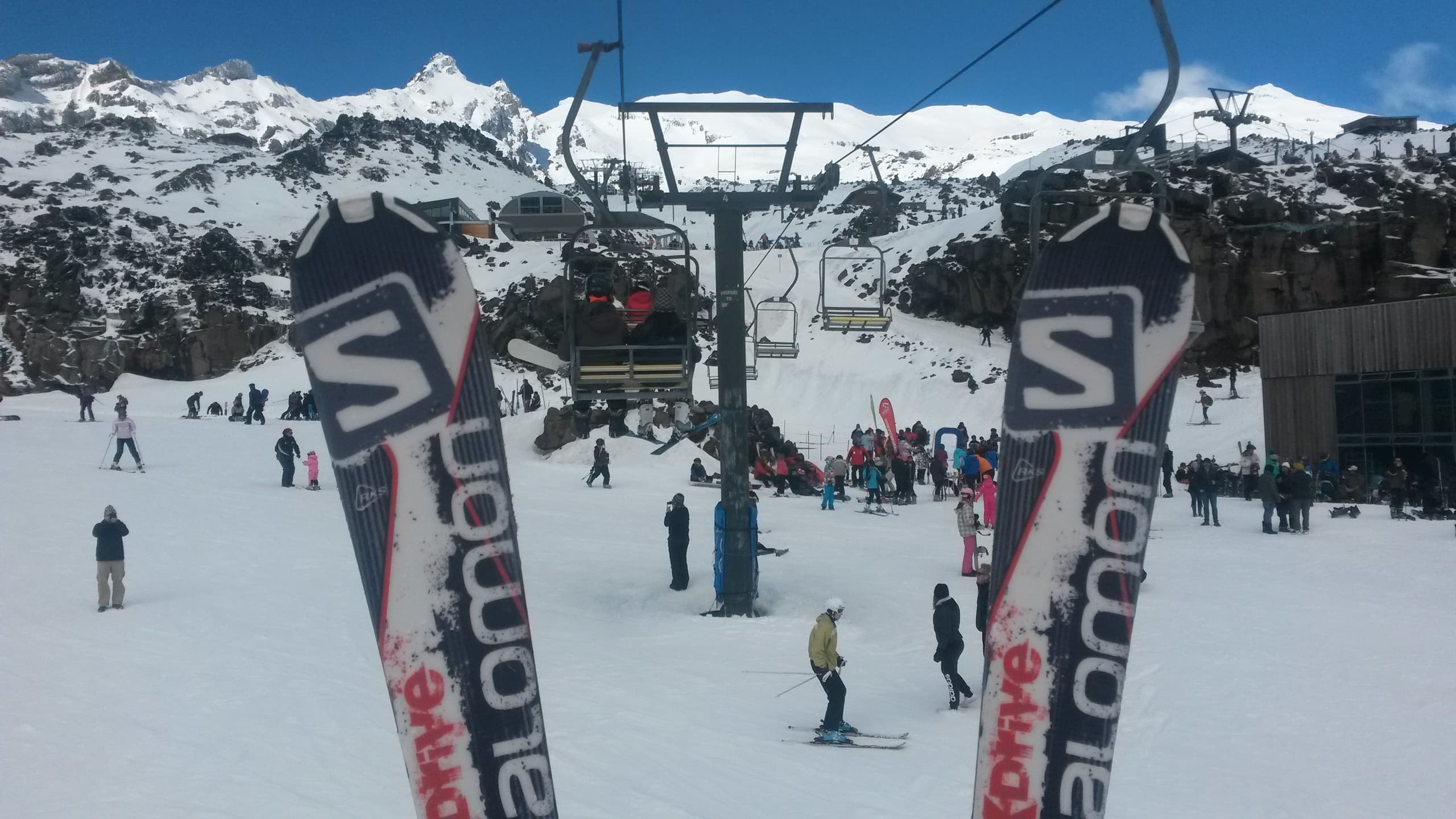Skier's skis planted in snow at busy alpine ski field base