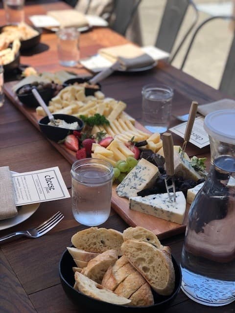 Closeup artisanal cheese board and bread at outdoor table tasting