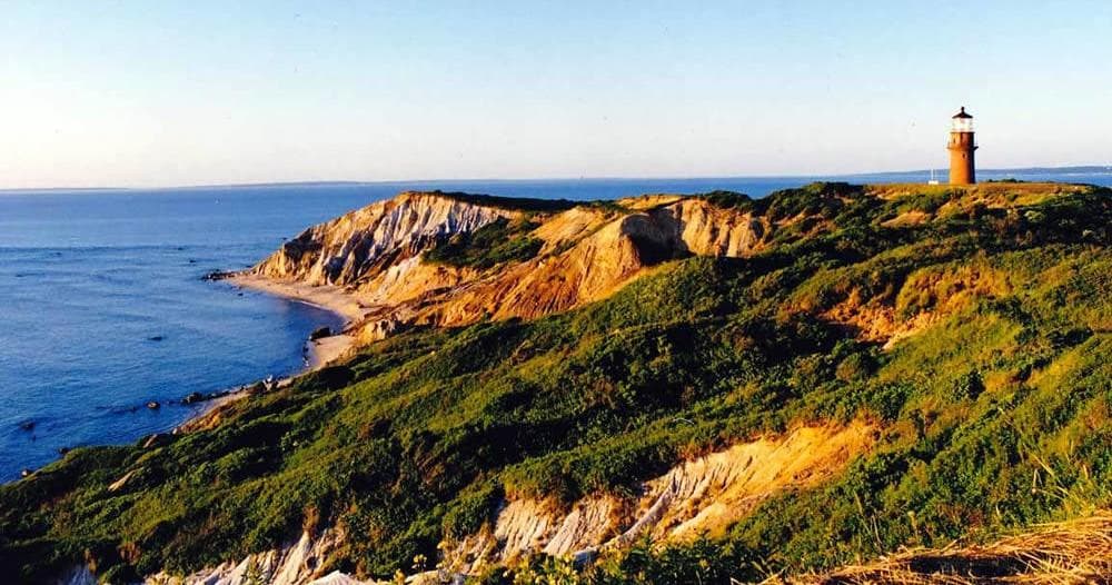Rocky coastline with distant lighthouse, scenic island photo spot