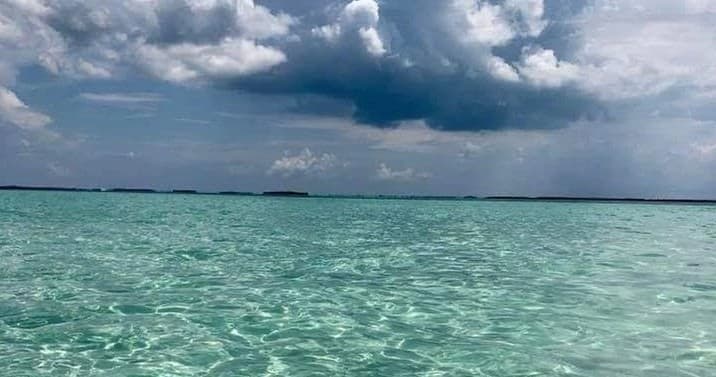 Turquoise tropical sea under dramatic storm clouds, scenic horizon
