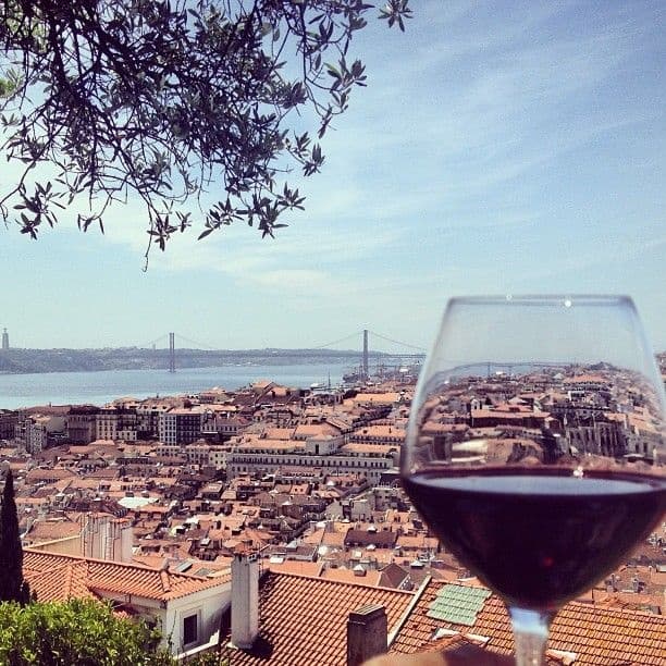 Glass of red wine overlooking Lisbon rooftops and Tagus Bridge view