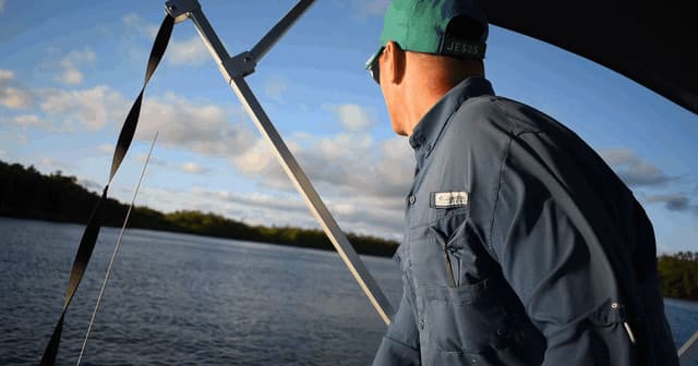 Captain scanning coastal shoreline from bow during daylight cruise