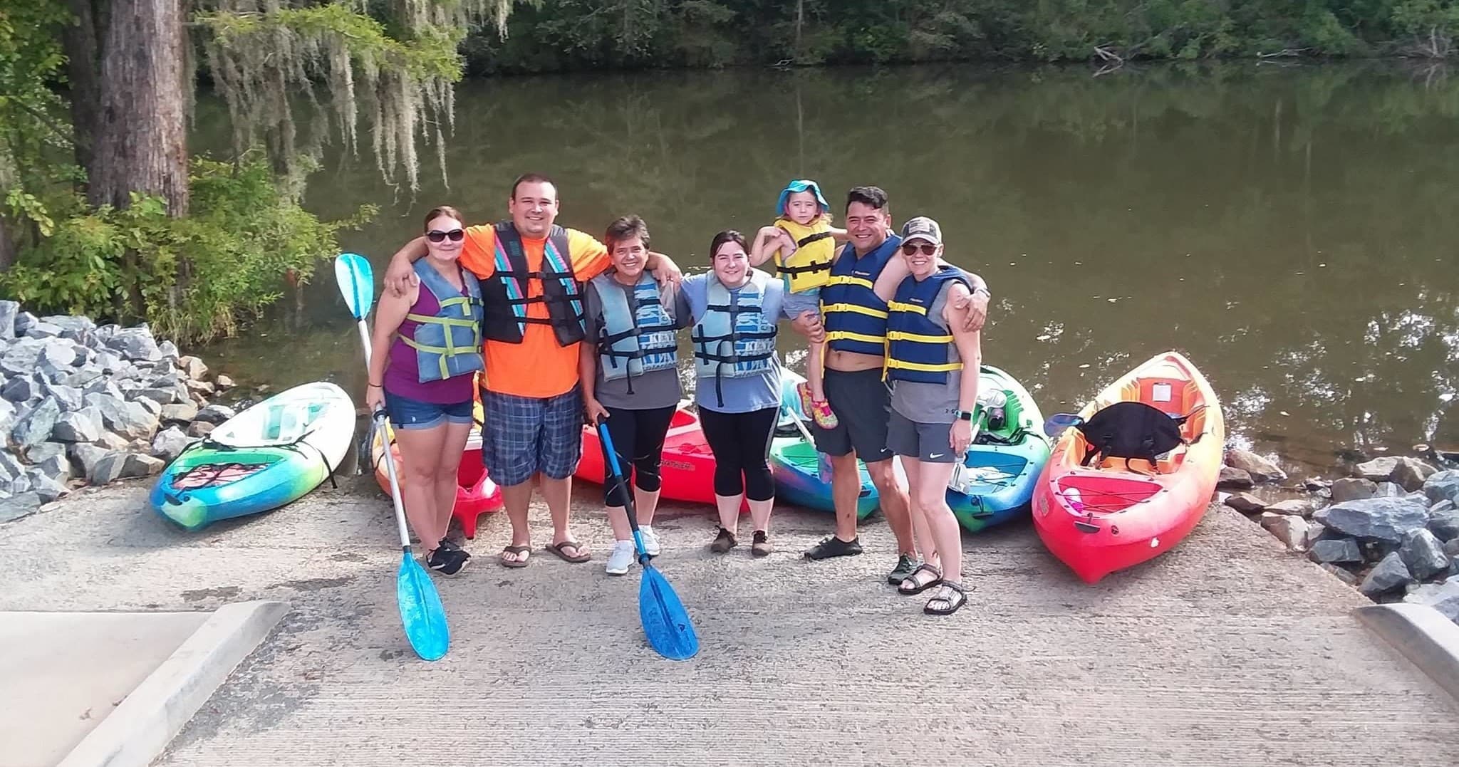 Group of kayakers posing at boat launch before river trip
