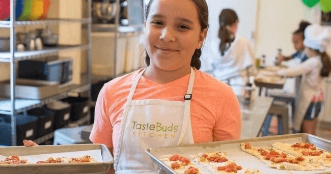 Girl showing homemade pizzas during youth indoor cooking class