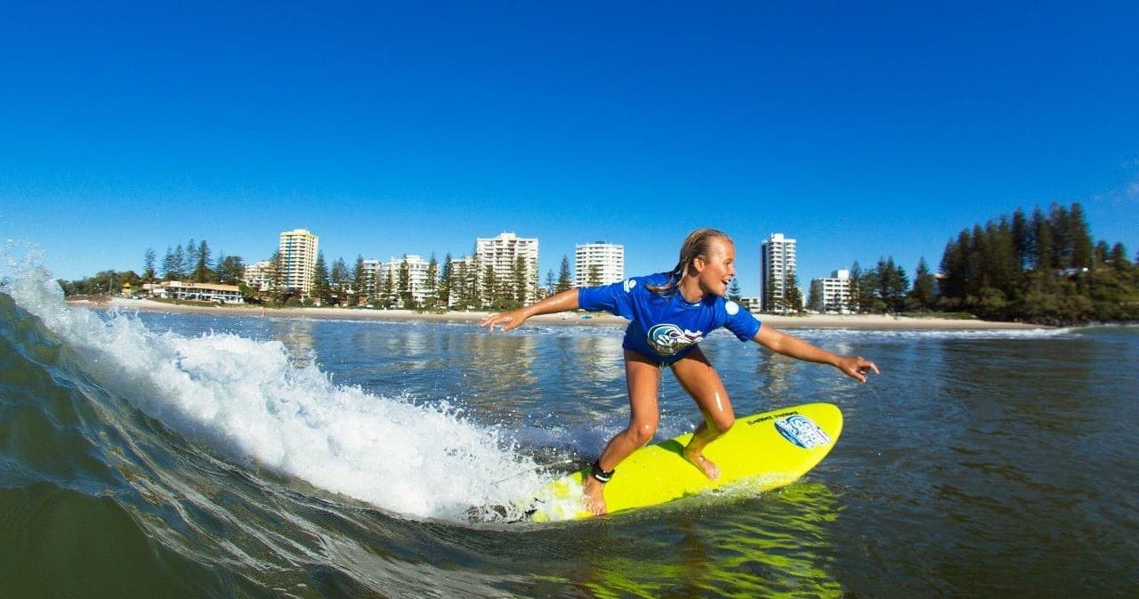Surfer riding a wave on a yellow board at coastal beach skyline