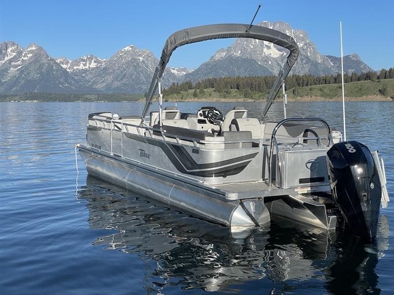 Pontoon boat docked on clear alpine lake with mountain reflections