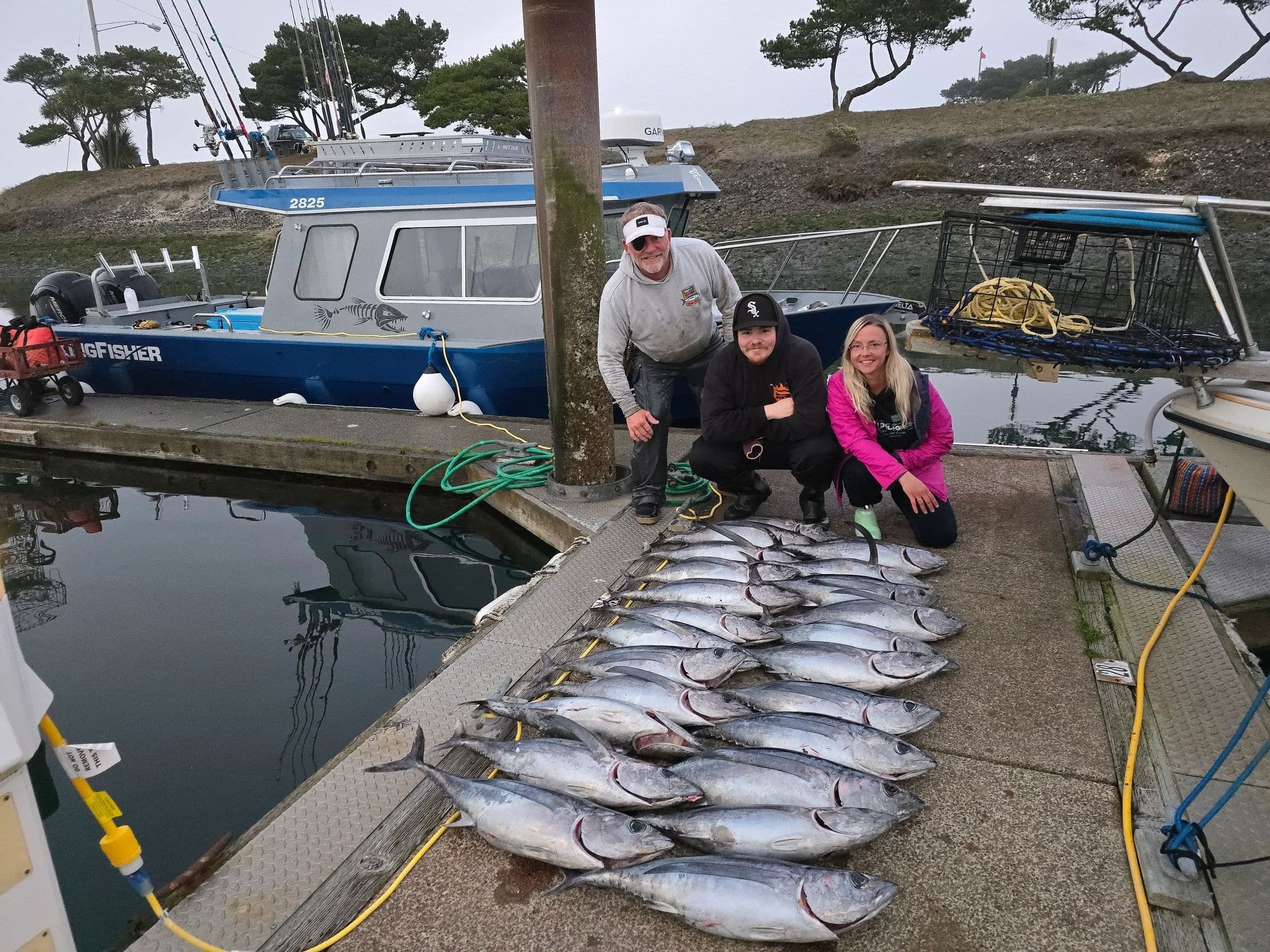 Charter anglers posing with a row of freshly caught tuna on dock