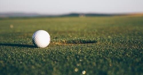 Close-up golf ball on green with shallow depth and sunlight