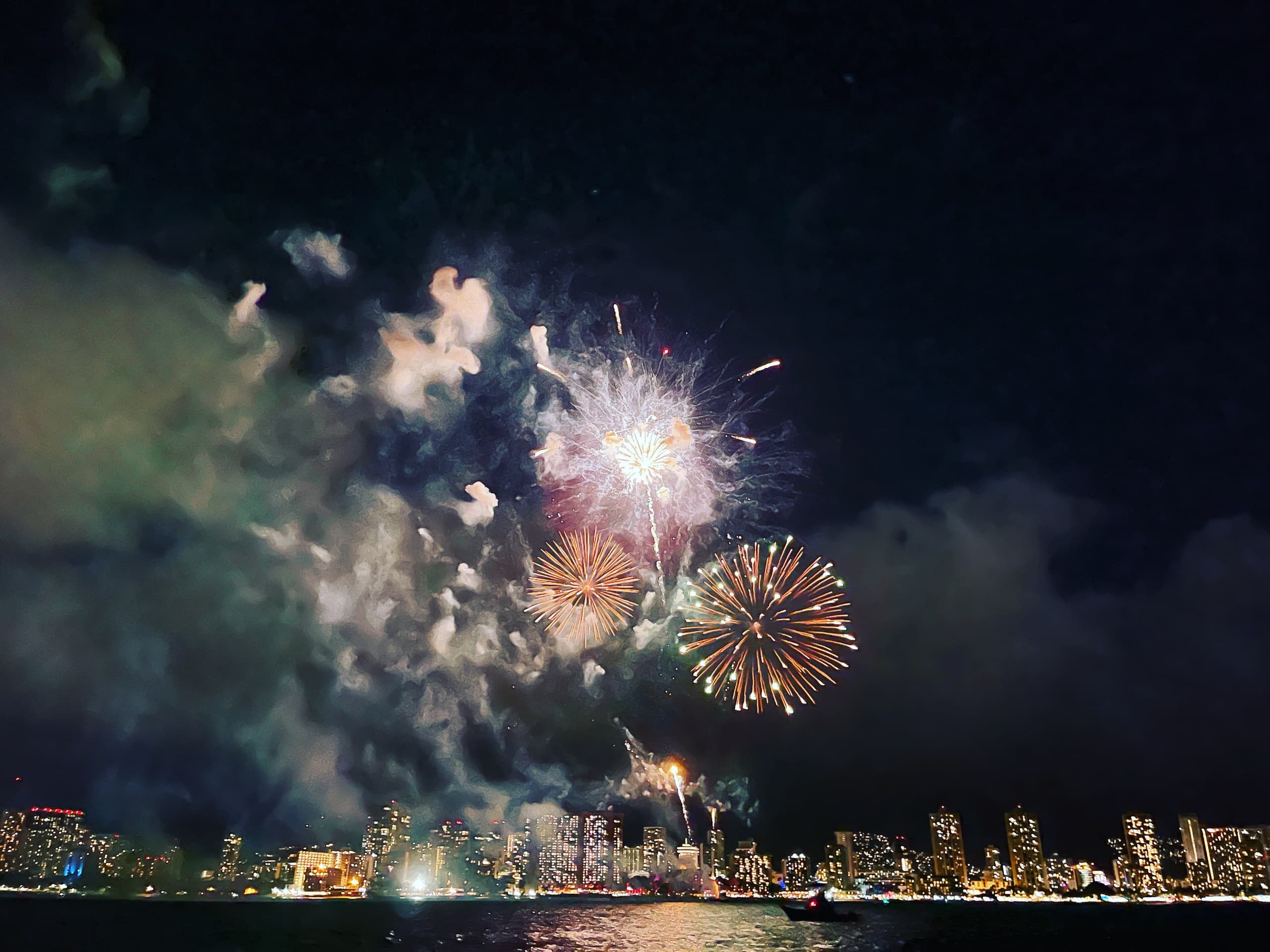 Fireworks bursting over waterfront city skyline at night