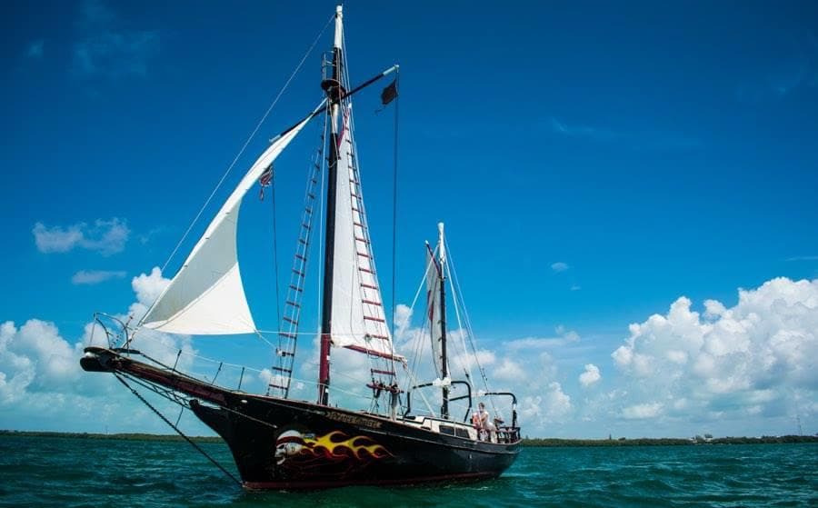 Traditional schooner cruising on open sea with dramatic clouds