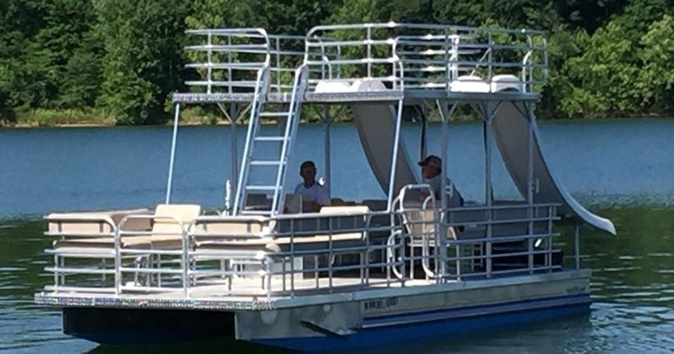 Two-story party pontoon with slide on a forested lake