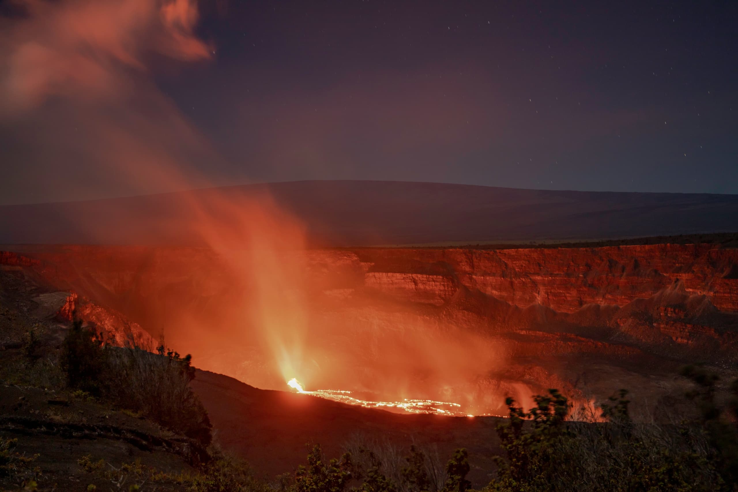 Nighttime glowing lava lake in active volcano crater experience