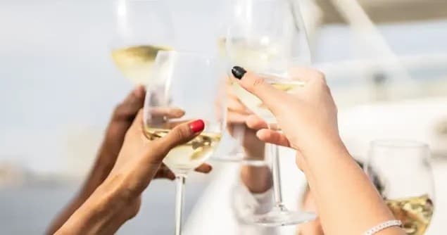 Hands toasting with white wine glasses aboard a leisure yacht