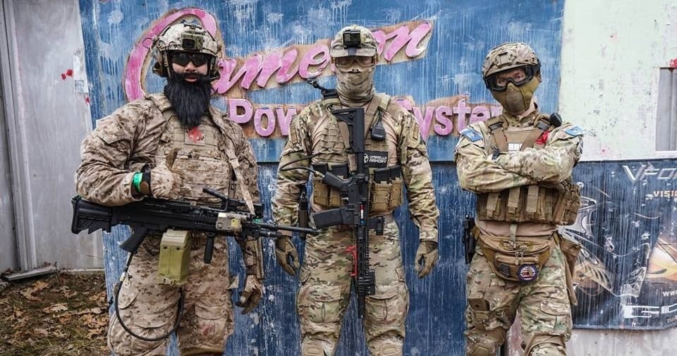 Three airsoft players in tactical gear at wooded field