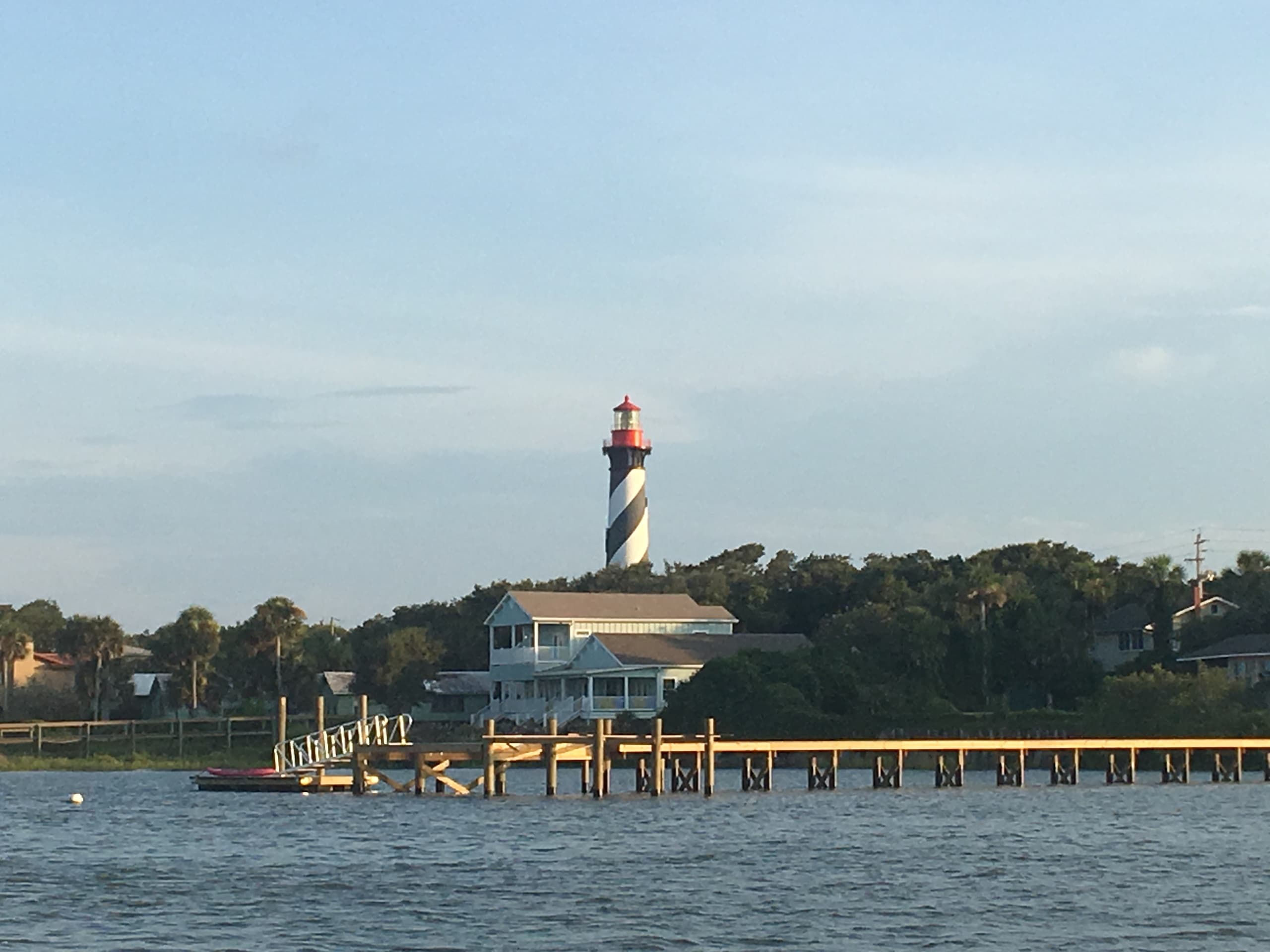 Historic St. Augustine lighthouse and riverside pier framed by clear sky