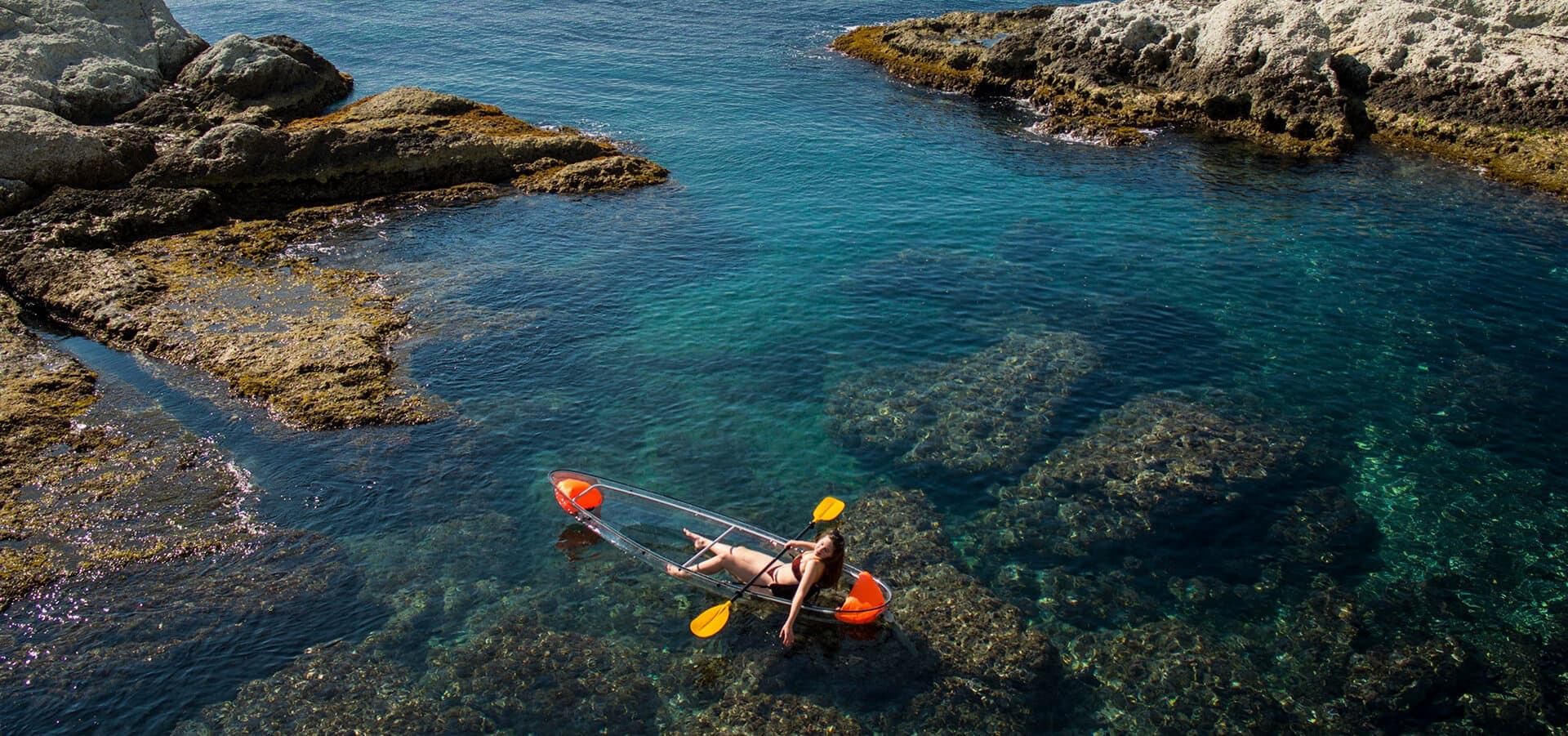 Clear kayak paddling in rocky coastal cove with turquoise water