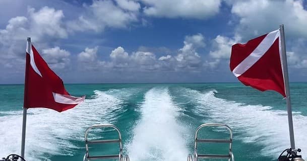 Scuba dive flags and boat wake on turquoise open ocean ride