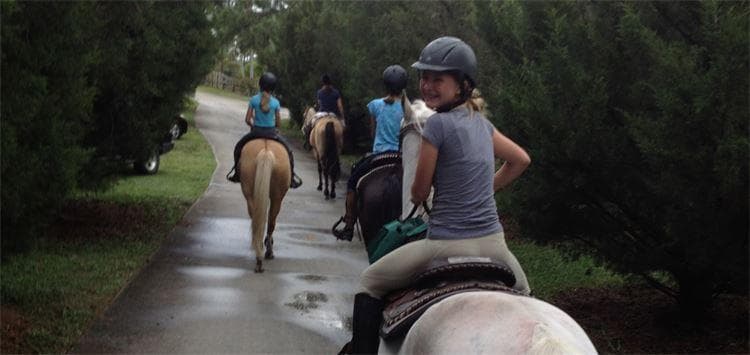 Trail ride with riders passing down shaded tree-lined path