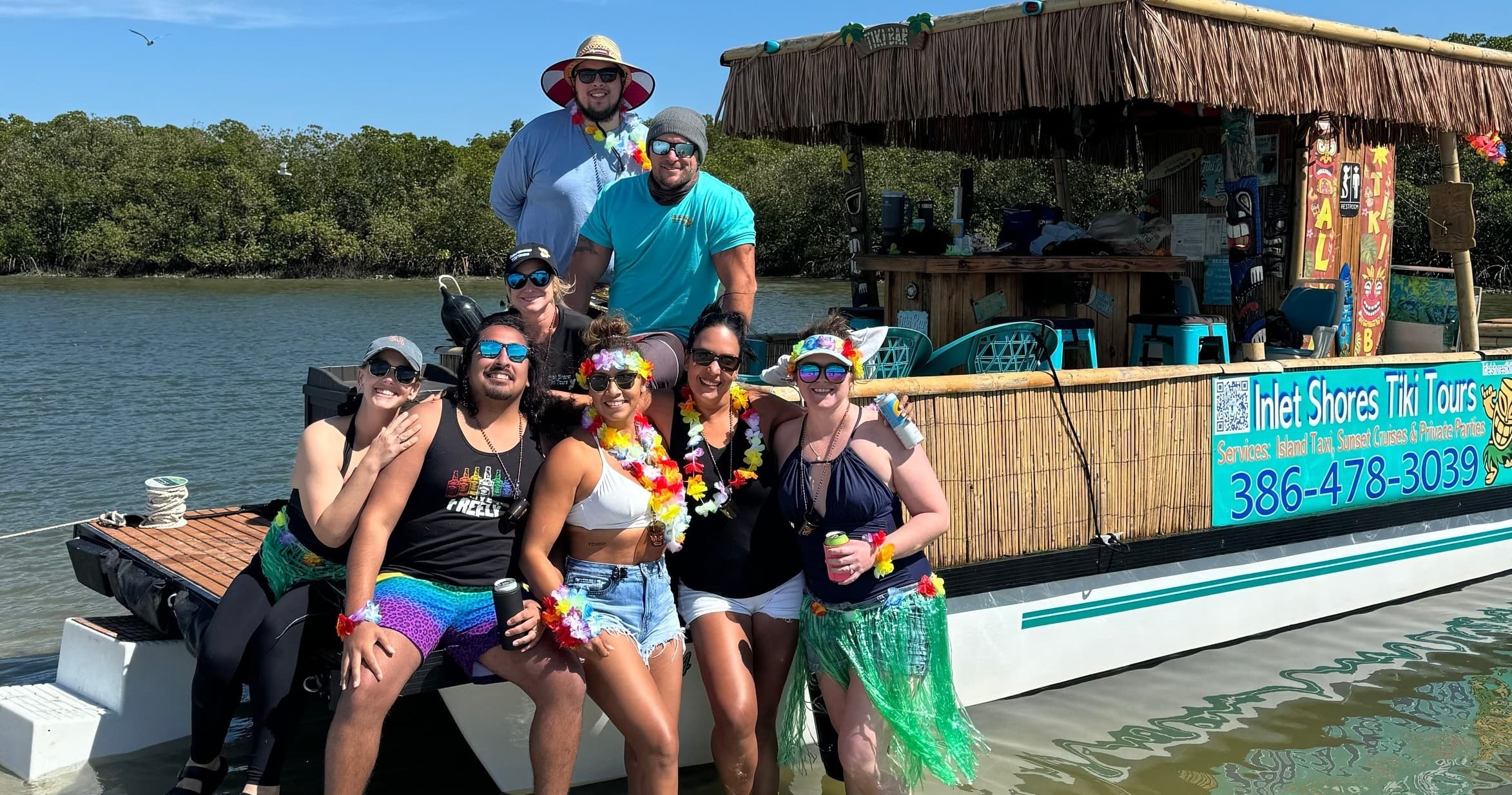 Group enjoying tiki boat tour on coastal inlet with mangroves
