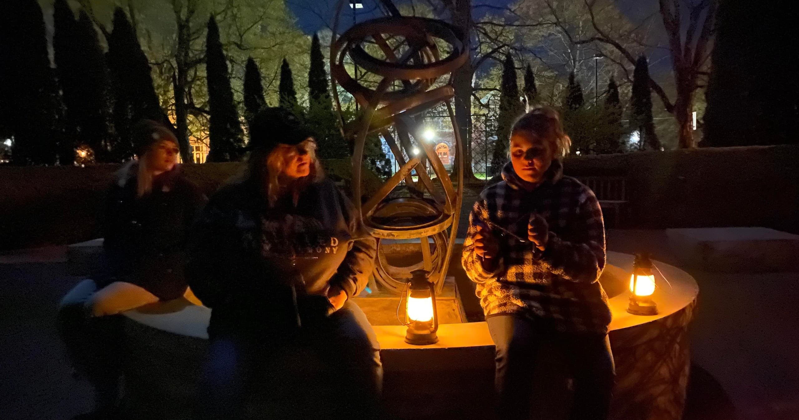 Small-group lantern ghost tour gathered outdoors in plaza at night