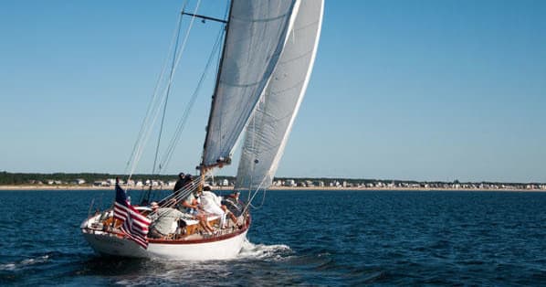 Sailboat cruising on open ocean with full sails and crew