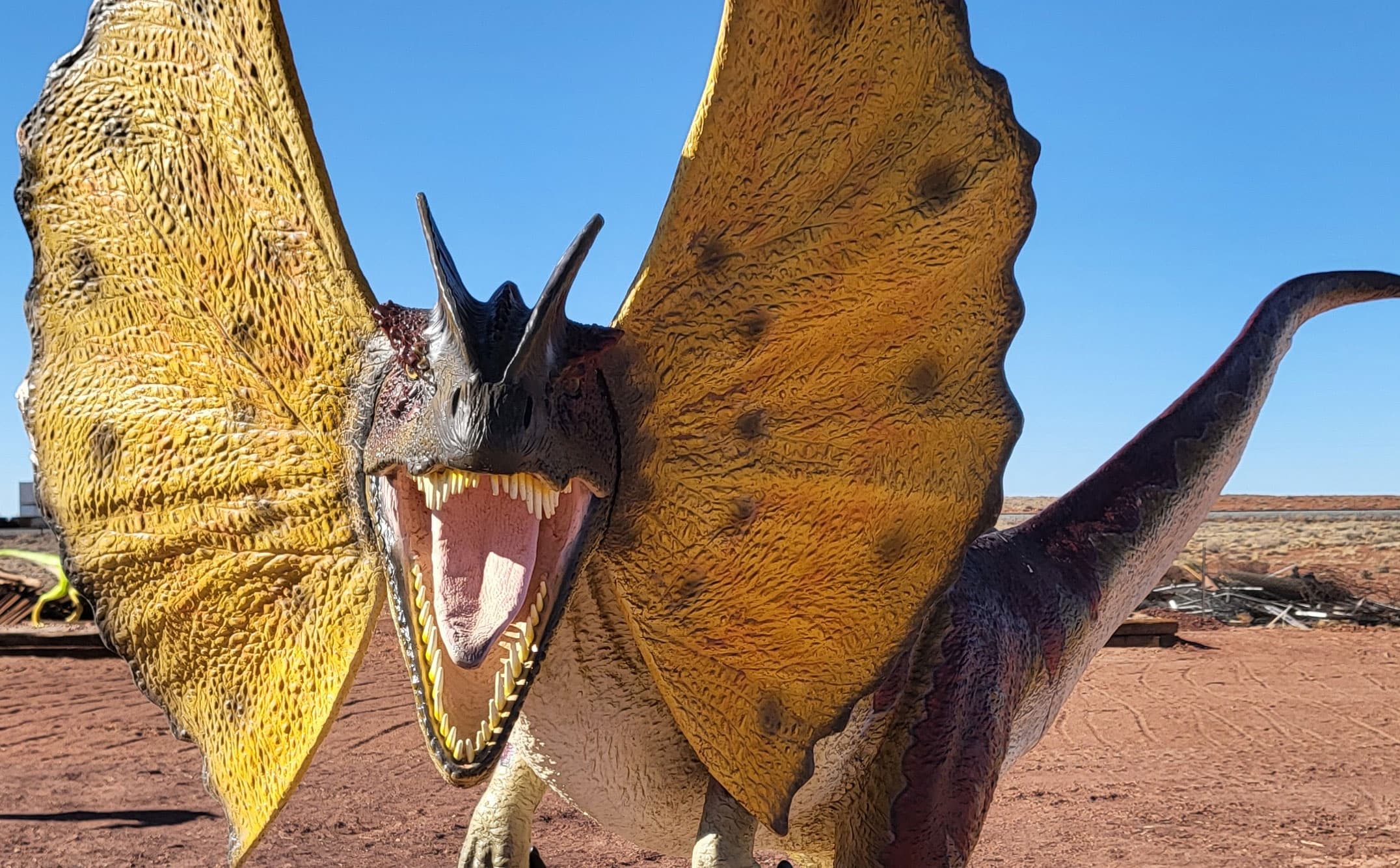 Dinosaur exhibit in desert, life-size raptor model roaring