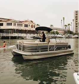 Pontoon boat cruising near waterfront restaurants in marina