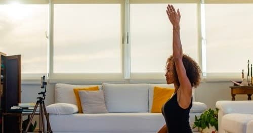 Solo yoga stretch in bright coastal living room studio
