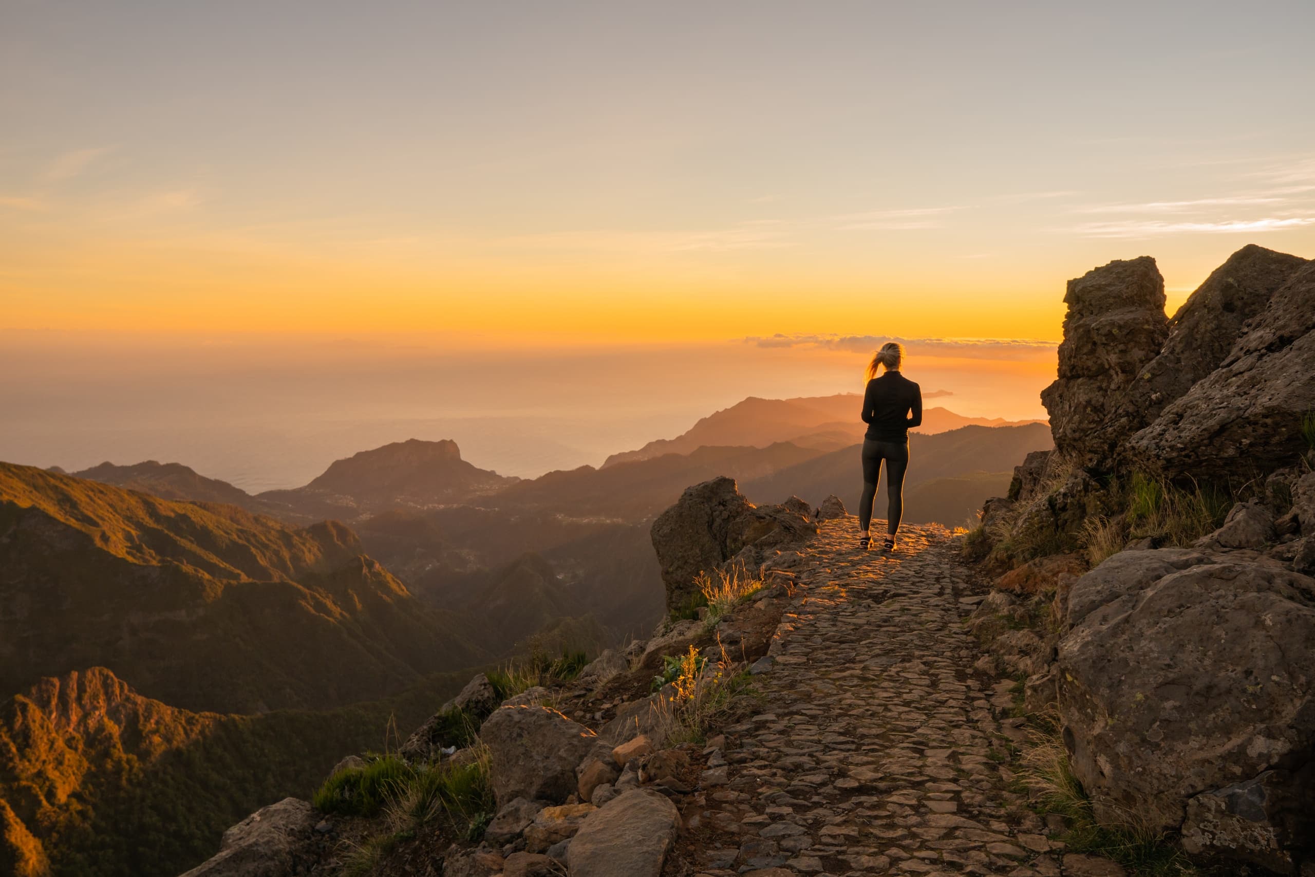 Sunrise ridge viewpoint with solo hiker on mountain trail