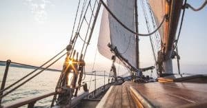 Wooden sailboat deck and rigging at sunrise on open ocean
