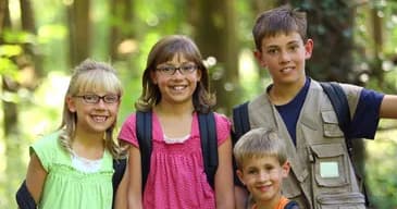 Children hiking and smiling on shaded forest trail