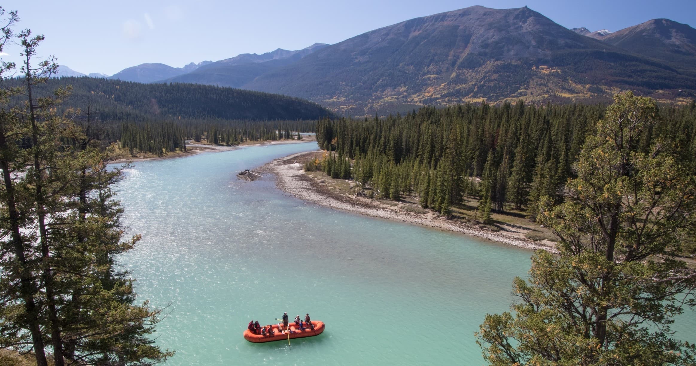 Rafting on turquoise mountain river in forested valley scenery