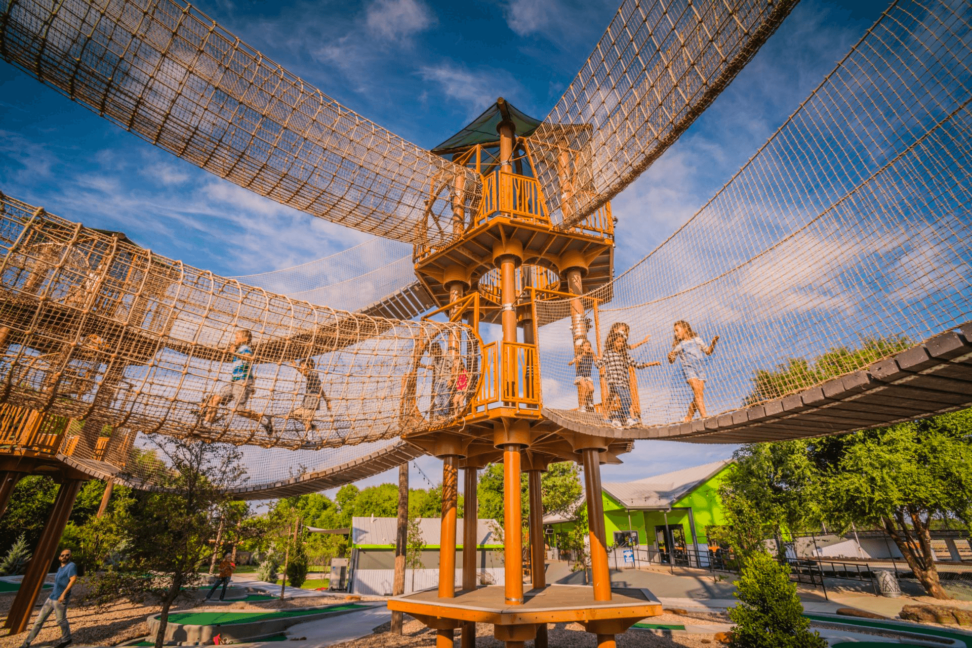 High ropes course tower above trees at sunny outdoor park