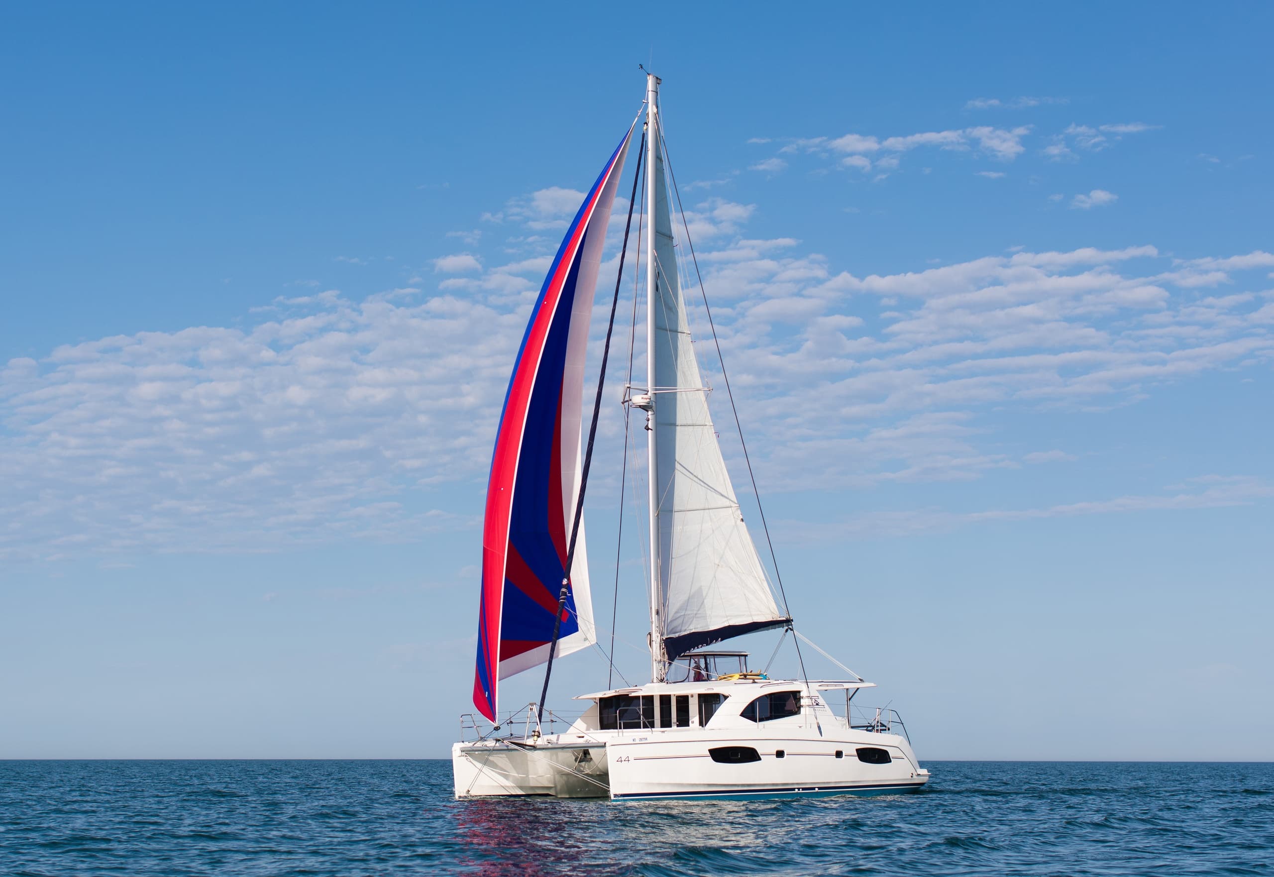 Sailboat cruising on open ocean under blue sky, coastal sailing