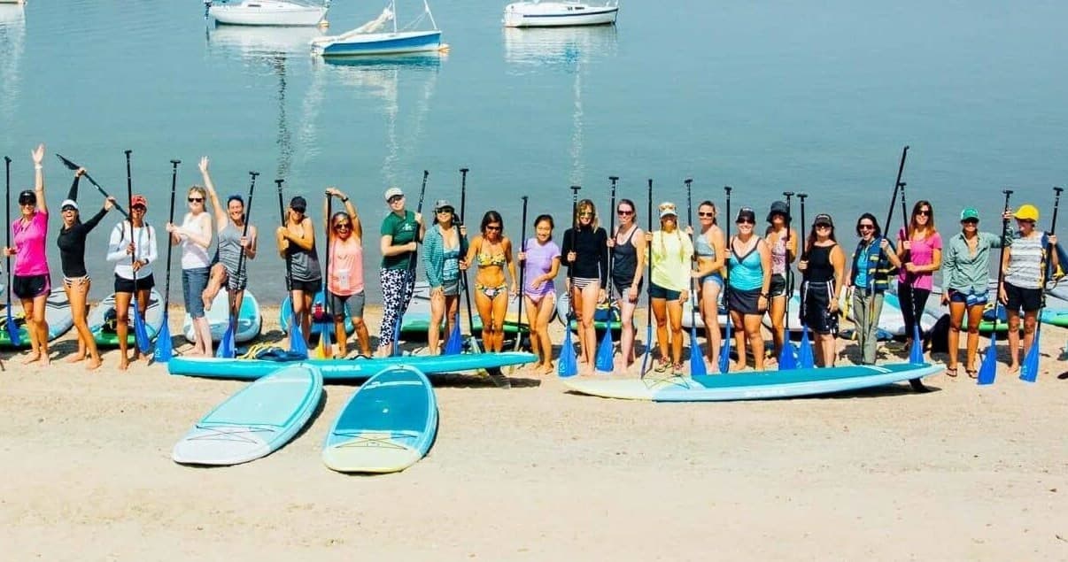 Crowd of paddleboarders on a sunny beach shoreline paddle tour