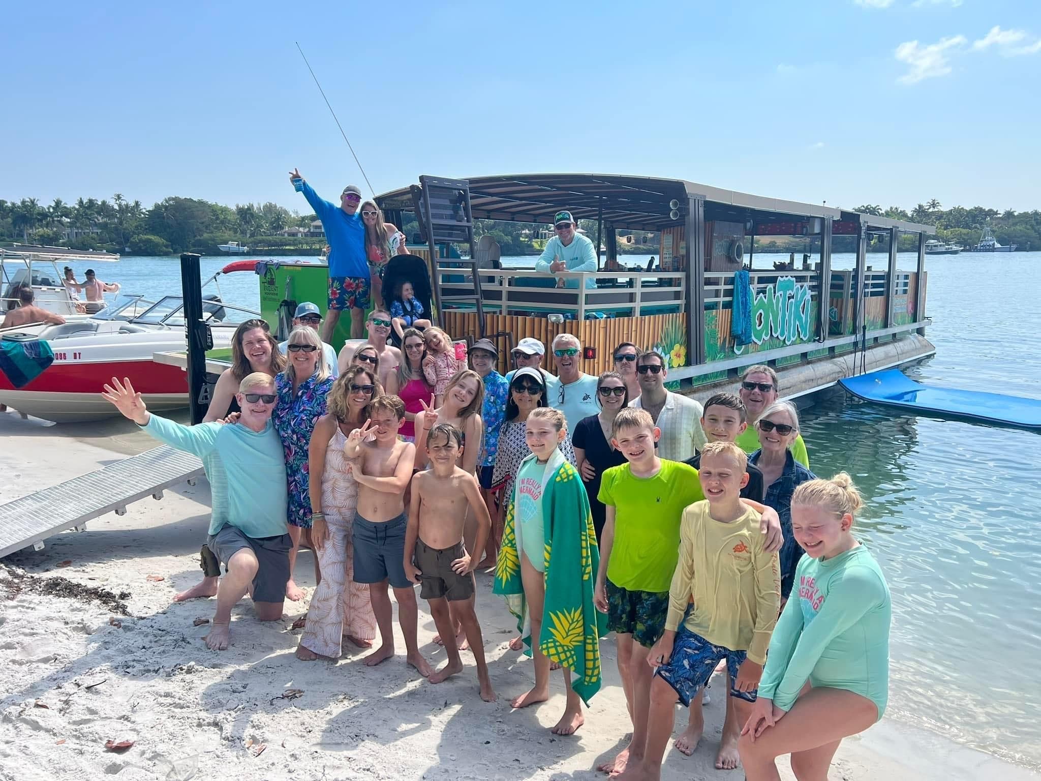 Beach group boarding pontoon boat at sunny coastal sandbar