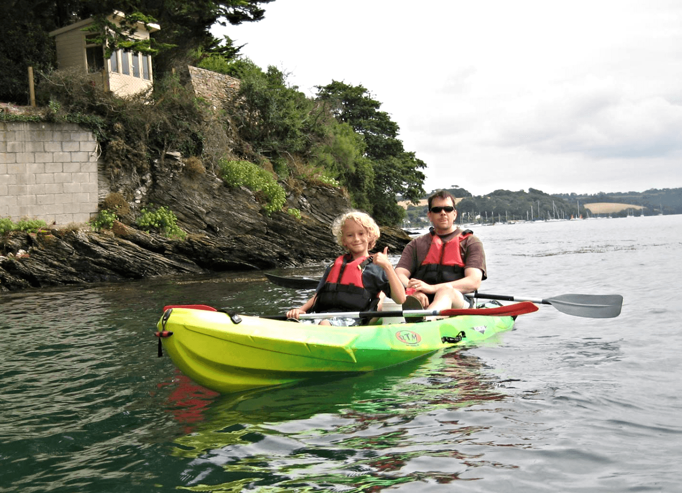 Two-person kayak near rocky shoreline on a scenic coastal paddle
