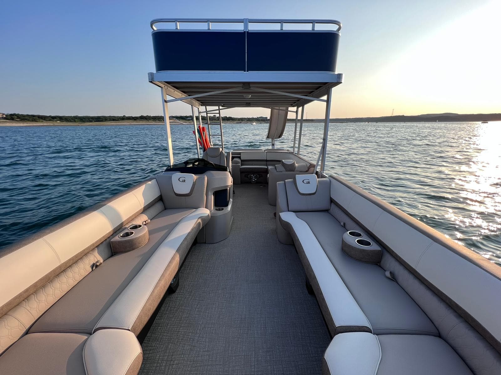 Sunlit pontoon bow seating with canopy on calm lake