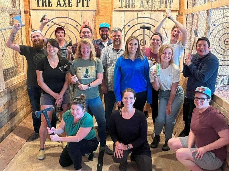 Team building axe throwing group photo inside fenced target lanes