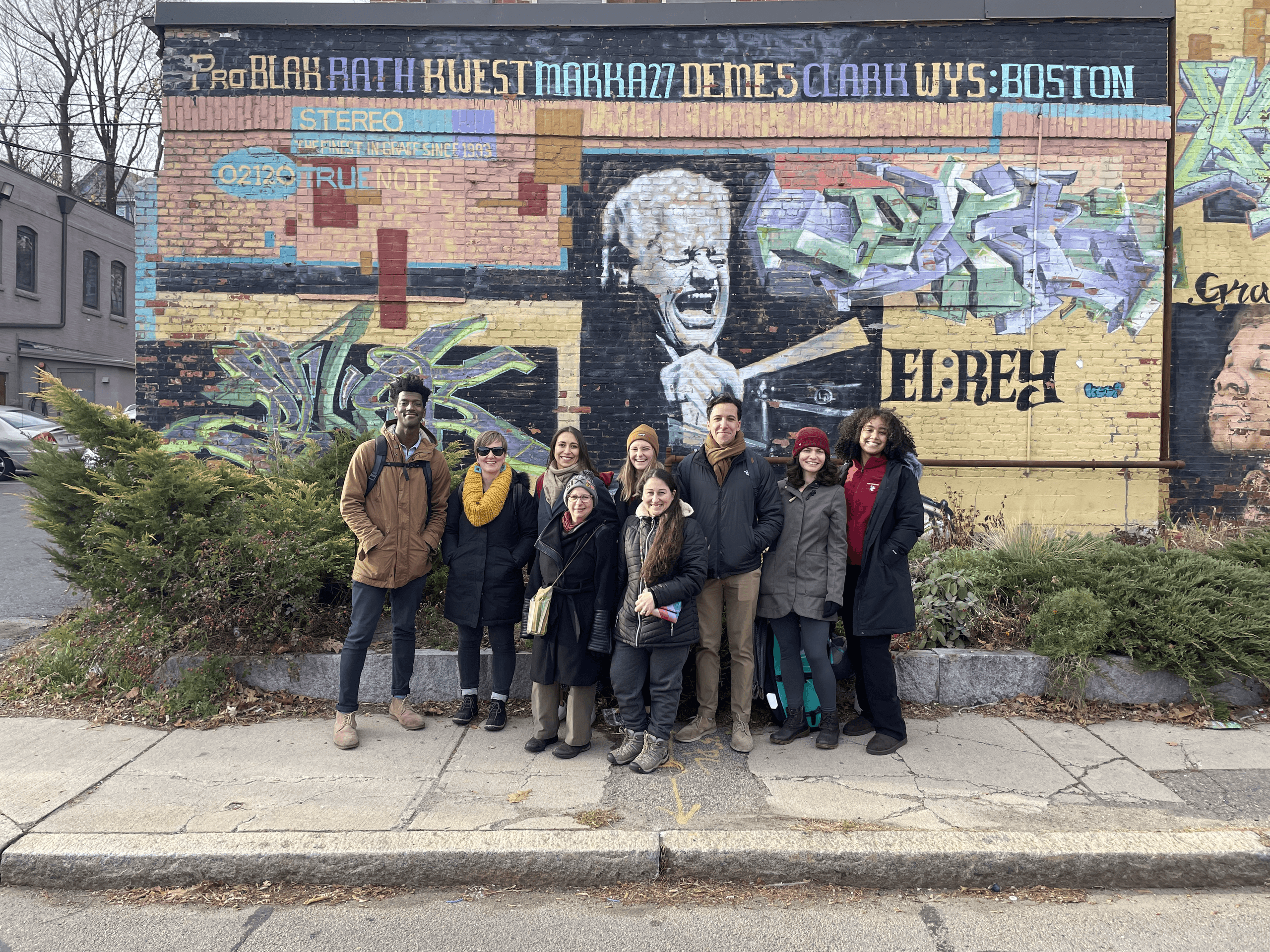 Small walking tour group paused by urban mural in Boston