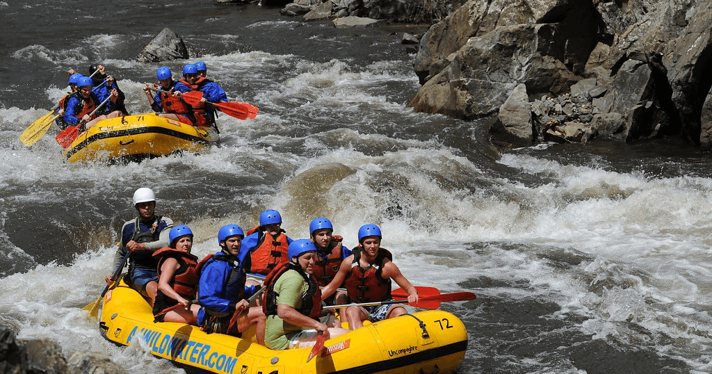Whitewater rafting group navigating rocky river rapids in canyon