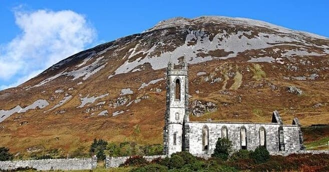Stone church ruins on grassy hillside in rural Northern Ireland