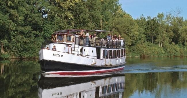 Historic tour boat cruising tree-lined Erie Canal near shore