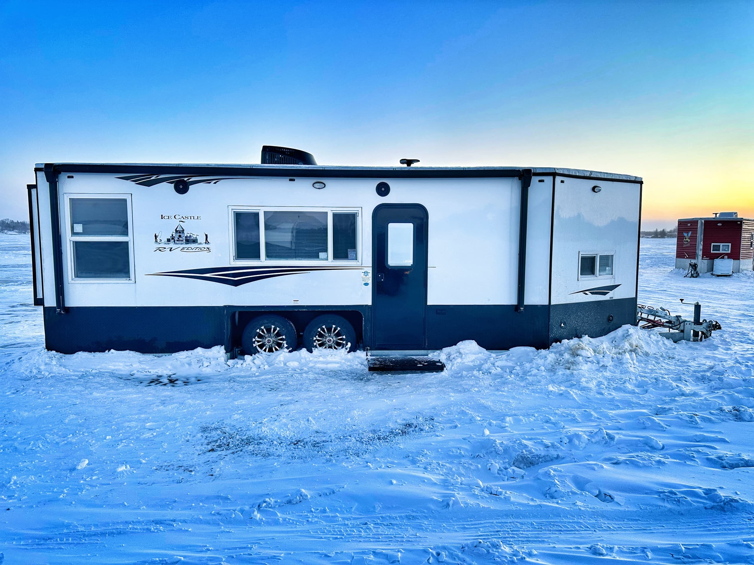 Parked ice travel trailer on frozen lake for winter anglers