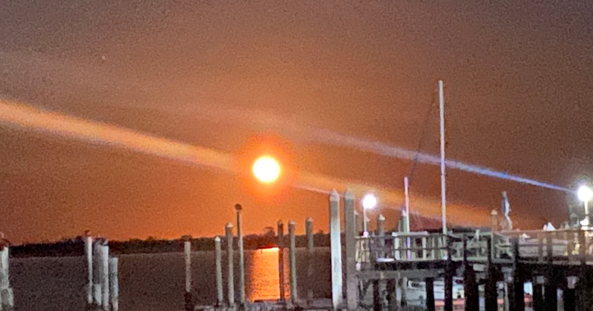 Full moonrise over marina docks with reflected water and evening glow