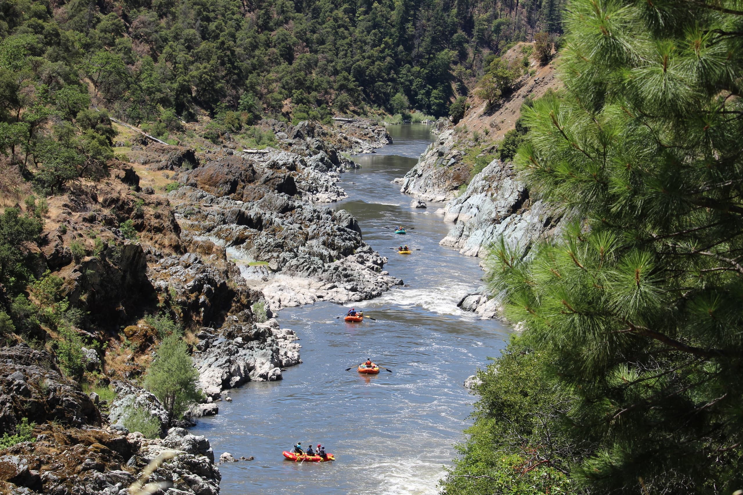 Aerial view of multiple rafts running a scenic rugged river gorge