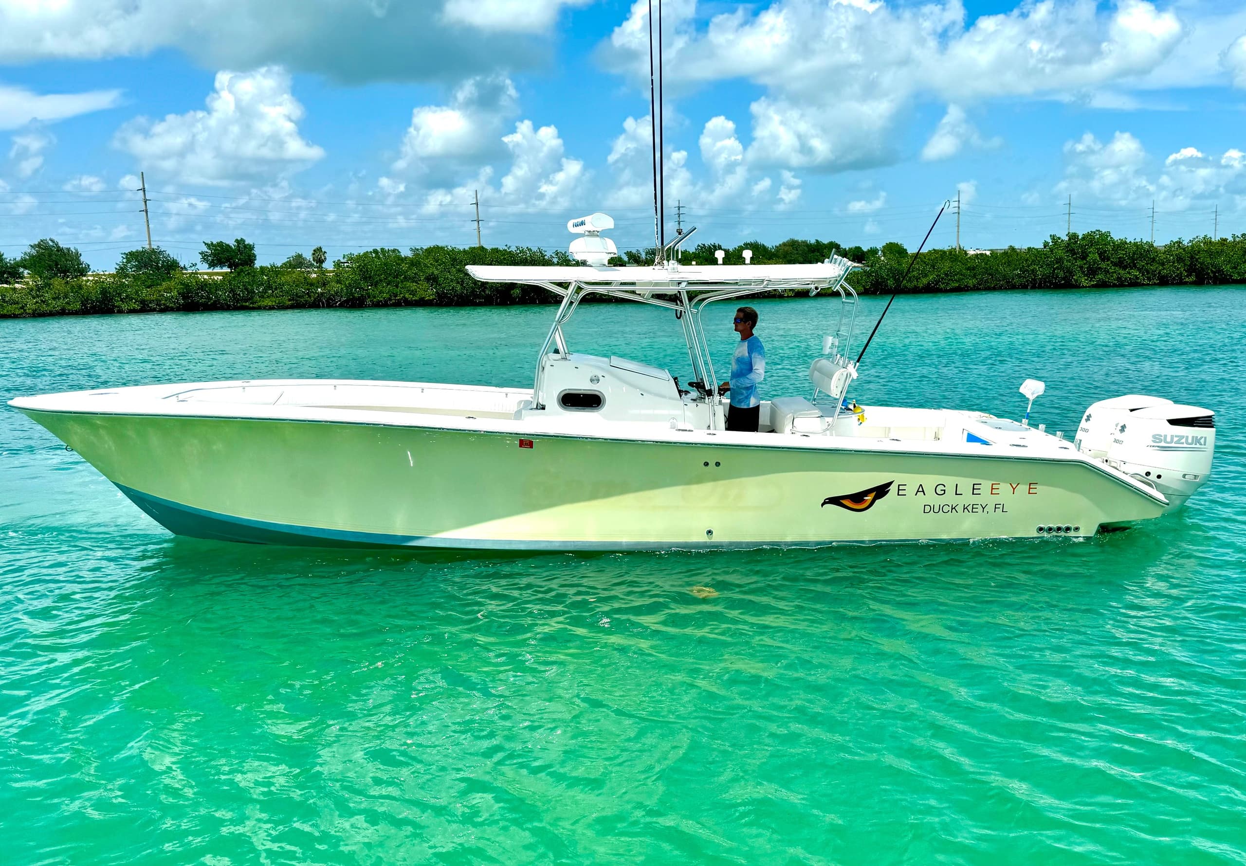 Twin-engined flats boat gliding in shallow emerald water, sunny