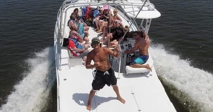 Crowded charter boat cruising with wake on open coastal waters