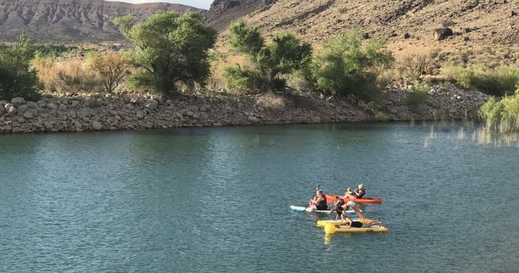 Small kayak group exploring tranquil reservoir near rocky banks