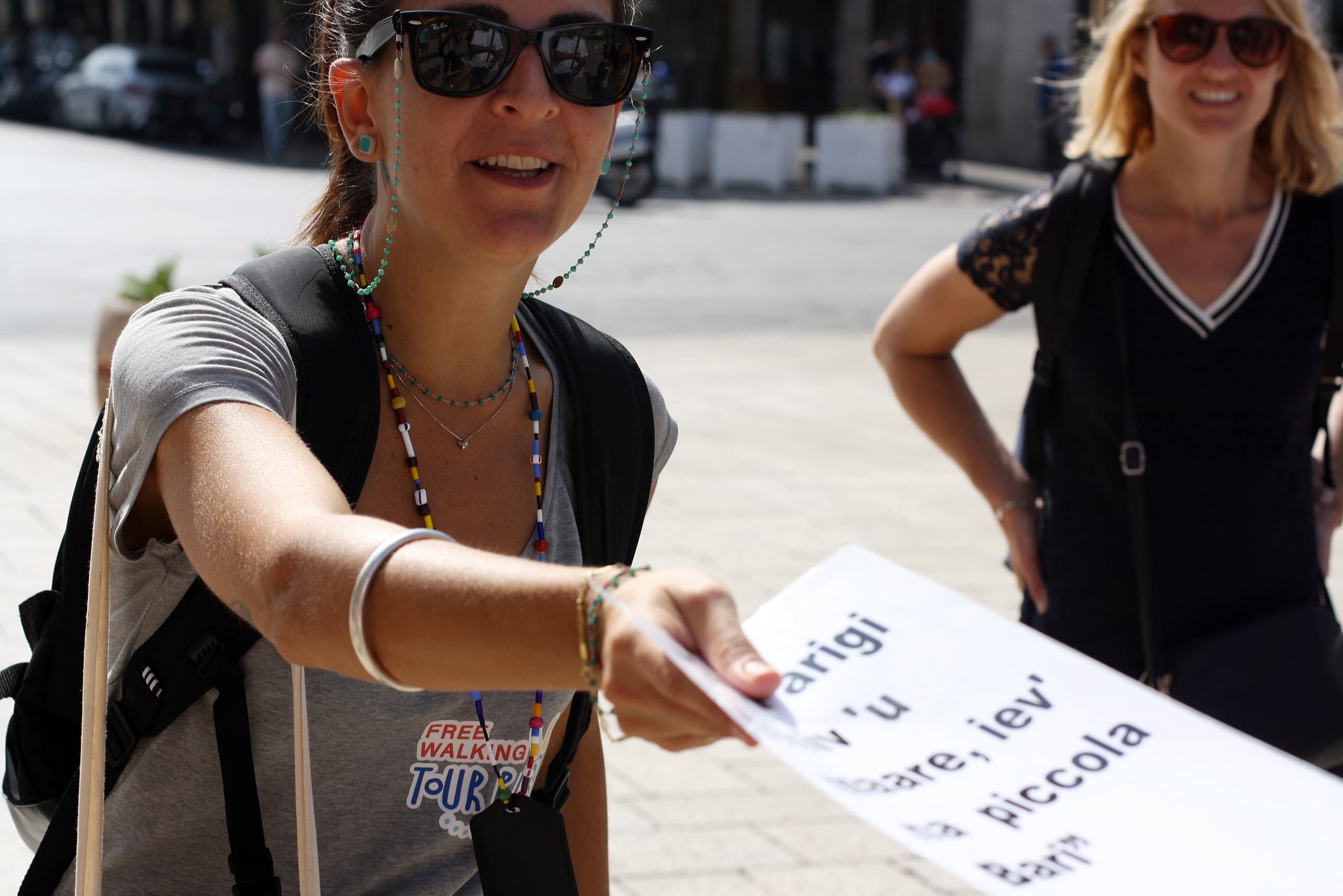 Tour guide handing map to visitor on Bari walking tour outdoors